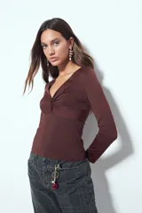 Top de manga larga color negro con escote en V y detalle de frunce central. Presenta un corte entallado que se adapta a la figura.