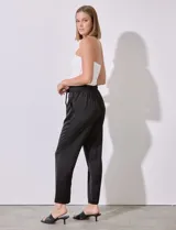 Pantalón negro de satén con pretina elastizada, lazo de ajuste y bolsillos inclinados.