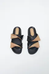 Sandalias planas con base negra y dos tiras anchas superiores, una color beige y otra negra, con efecto arrugado.