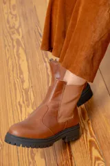 Bota tipo chelsea de cuero color chocolate con acabado brillante, paneles laterales elásticos y suela track negra de goma.