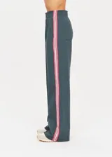 Pantalón deportivo ancho azul con cintura elástica, bolsillos laterales y traseros, y cinta de rayas blancas y rojas en las costuras laterales.