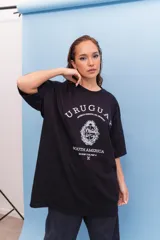 Remeron negro de corte oversize con estampa frontal en color blanco que incluye la palabra Uruguay, el escudo nacional y coordenadas geográficas.