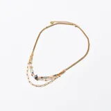 Collar dorado de múltiples cadenas, con cuentas de colores y dijes colgantes.
