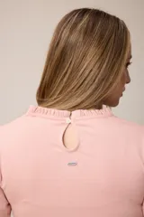 Remera de manga larga color rosado, con cuello redondo y puños con detalle de volados fruncidos.