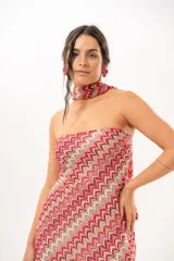 Vestido largo de crochet con escote strapless y lazo integrado para el cuello, con diseño de patrón en zigzag en tonos rojos, blancos y beige, y aberturas laterales en la falda.
