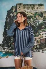 Buzo color beige con rayas horizontales en lurex dorado, cuello con medio cierre, corte oversized y logo tejido en el puño.