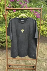 Remera de algodón premium color negro con efecto lavado, de manga corta y corte holgado. Presenta un estampado gráfico en la espalda con el texto 'Good Trips, Good Friends' y una ilustración de personajes apilados.