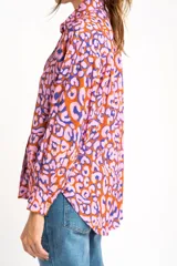 Camisa de viscosa color naranja con estampado animal print en tonos rosa y azul. Corte oversize, cuello clásico y cierre frontal con botones.