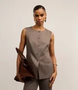 Chaleco regular color marrón claro con estampa de cuadros, confeccionado en punto roma, con cuello redondo, abotonado delantero con botones forrados y recorte en la bajo.