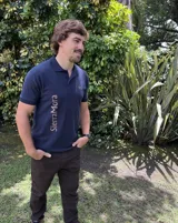 Remera tipo polo azul marino con cuello y puños acanalados en el mismo tono, mangas cortas. Cuenta con el nombre de la marca impreso en vertical sobre el lado derecho del frente y un bordado pequeño en el pecho izquierdo.