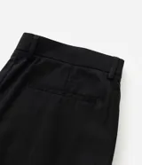 Pantalón de sastrería color negro, de corte recto y fluido. Presenta cintura estructurada con trabillas, cierre frontal con botón y cremallera, pliegues delanteros y bolsillos laterales funcionales.