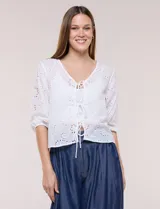 Cardigan corto de broderie blanco con escote en V y cierre frontal de lazos para anudar. Presenta mangas tres cuartos abullonadas con puño elástico y diseño perforado con motivos florales.