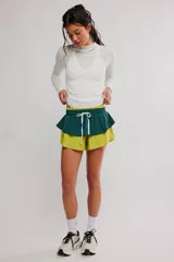 Short deportivo de poliamida en color verde militar, con capa superpuesta tipo falda en verde oscuro. Cuenta con cintura elástica y cordón ajustable blanco.
