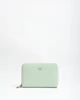 Billetera compacta de símil cuero color verde menta, con cierre perimetral y logo metálico de la marca en el frente.