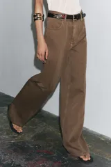 Pantalón de jean color marrón, de tiro alto, corte wide leg y relaxed fit. Cuenta con bolsillos delanteros y traseros, trabillas en la cintura, cierre frontal con cremallera, botón interior y gancho metálico.