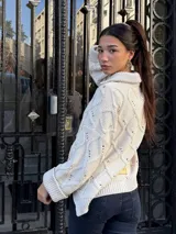 Saco tejido de punto con diseño de ochos y trenzas, color negro. Presenta cuello estilo camisero, cierre frontal con botones tipo joya, mangas holgadas y silueta oversize.