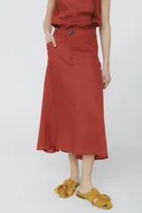 Falda midi de corte acampanado en color cereza, con cintura alta, cierre frontal con botón y bolsillos laterales.