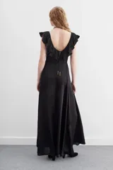 Vestido largo negro de escote redondo con volados decorativos que recorren el frente y la espalda. Presenta un cordón de ajuste en la cintura con terminaciones metálicas y espalda baja.