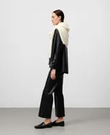 Pantalón negro de efecto cuero, corte flare o acampanado, largo hasta el tobillo. Presenta bolsillos de vivo en la espalda y cierre lateral de cremallera.