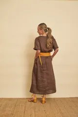 Vestido tipo túnica largo de lino, color bordo, con mangas cortas, bolsillos laterales y detalle de volados en la botonera frontal.