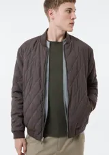 Campera bomber reversible, de diseño acolchado con costuras romboidales, cierre frontal completo y bolsillos laterales.