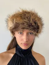 Gorro tipo banda de piel sintética en tonos marrones y beige, con textura voluminosa y diseño envolvente.