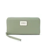 Billetera larga con cierre perimetral, confeccionada en material sintético texturizado color mostaza. Cuenta con correa de mano extraíble y placa metálica con logo de la marca en el frente.