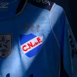 Camiseta de fútbol Umbro del Club Nacional de Football, edición especial celeste 2026. Diseño en color celeste con detalles en azul marino y blanco, con tejido jacquard inspirado en los 19 departamentos de Uruguay. Incluye el escudo del club, logo de Umbro, sponsors y emblemas oficiales en el frente.
