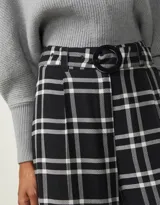 Pantalón de vestir negro con estampado de cuadros blancos, corte palazzo y cintura alta con cinturón.