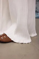 Pantalon tejido de punto en color blanco, de corte recto y holgado, con cintura elástica y cordón ajustable. Presenta una textura acanalada y terminación con volados sutiles en la botamanga.