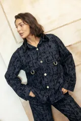Camisa recta de gabardina con efecto "roto", que aporta volumen y textura. Presenta bolsillos amplios con solapa en el frente adornados con mini estribos dorados y cierre frontal de botones.