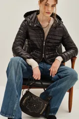 Campera puffer negra con capucha, cierre frontal con doble cremallera y diseño entallado en la cintura.