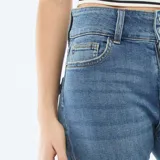 Jean de corte bootcut con tiro bajo, color azul medio con efecto lavado. Presenta cierre de doble botón y bolsillos clásicos.