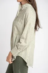 Camisa de corte oversize con estampado de rayas verticales, cuello clásico, cierre frontal con botones y bolsillo en el pecho. Presenta mangas largas con puños abotonados y un diseño fluido.