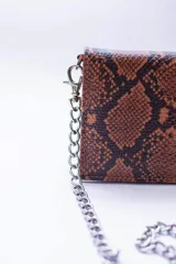 Cartera negra con textura símil cocodrilo y cadena metálica plateada.