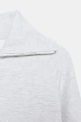 Chaqueta de felpa negra con cuello solapa, manga larga con puño, bolsillos de plastrón en el delantero y cierre frontal con cremallera.