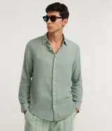 Camisa de manga larga para hombre de corte comfort, color verde, confeccionada en algodón con textura melange, cuello inglés y cierre frontal con botones.