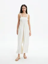Monoprenda larga color blanco off white, con escote cuadrado y cuerpo estilo nido de abeja elástico. Presenta tirantes anchos y perneras amplias y sueltas.