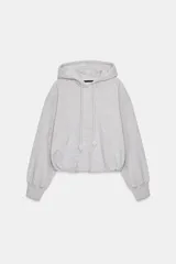 Sudadera de corte holgado con capucha ajustable mediante cordones con detalle de perlas en los extremos. Presenta mangas largas con puños elásticos y bajo con acabado tipo globo.