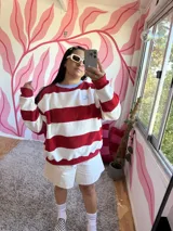 Buzo deportivo a rayas horizontales rojas y crudas, con cuello redondo celeste y logo bordado en el pecho.