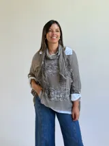 Sweater de punto color visón con diseño superpuesto, que incluye una bufanda integrada y detalles de encaje floral en el frente. Presenta mangas tres cuartos con puños abotonados y un corte holgado.