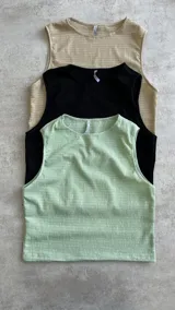 Musculosa corta de tejido de punto color rosa pálido con textura acanalada horizontal.