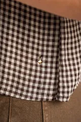 Blusa de algodón con estampado de cuadros vichy en tonos negro y blanco. Presenta escote en V, cierre frontal con botones y mangas cortas abullonadas con terminación elástica.
