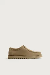 Zapato de cordones fabricado en piel con acabado en serraje, color beige, con detalle de bordón en el empeine, horma redonda y suela track a tono.