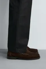 Mocasín de vestir para hombre, color marrón oscuro, fabricado en piel con acabado serraje (gamuza). Presenta un antifaz en el empeine con costuras visibles y suela a contraste con ligero tacón.