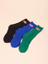 Pack de tres pares de medias de caña media, en color negro, azul y verde. Cada par presenta el logo de la marca Rusty bordado en el lateral.