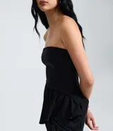 Blusa peplum sin tirantes de color negro, confeccionada en bengalina con diseño asimétrico en el dobladillo.