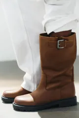 Bota de caña alta de piel color marrón con efecto desgastado, suela gruesa track engomada y detalle de hebilla metálica lateral en la parte superior de la caña.