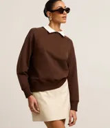Sweater marrón de algodón con cuello camisero blanco, corte recto y mangas largas raglán.