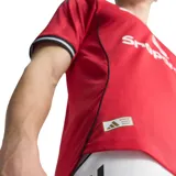 Camiseta de fútbol Adidas del Manchester United, modelo Local 25/26. Diseño rojo con detalles negros y blancos en cuello y mangas. Incluye logo de Adidas, escudo del club y sponsor Snapdragon en el frente.